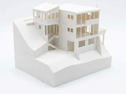White 3D-printed model of a three-story hillside home with exterior stairs and balconies, printed from photos of the real house